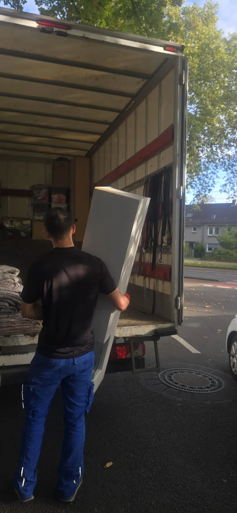 Mitarbeiter trägt ein Möbelstück zum LKW